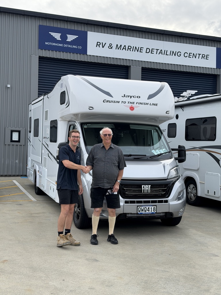Happy customer shaking hands with detailer in front of freshly detailed Jayco motorhome at the RV & Marine Detailing Centre