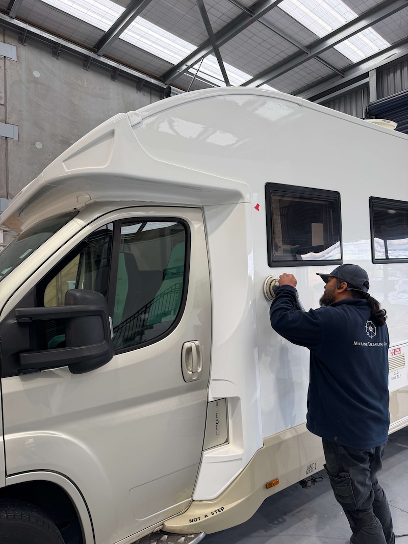 Machine polishing motorhome exterior panel in Auckland workshop