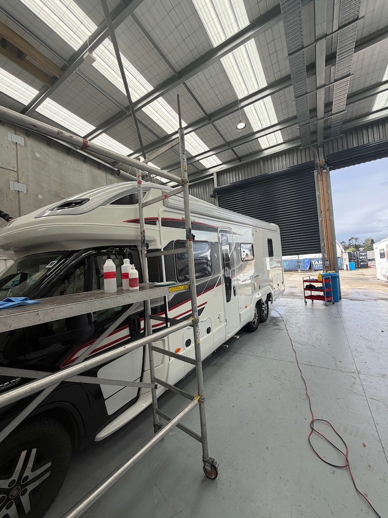 Multi-stage polish in progress on large motorhome with scaffold
