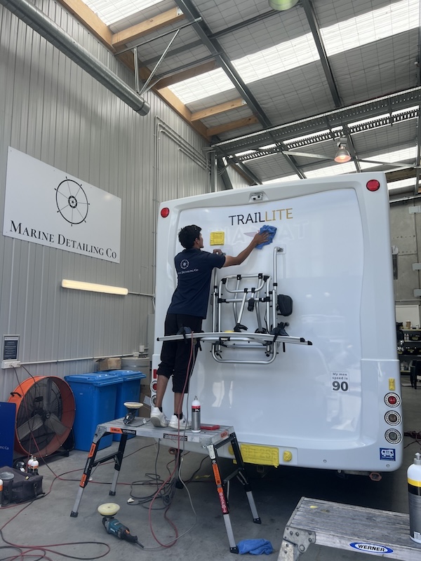 Detailer polishing the rear of a TrailLite motorhome at Marine Detailing Co